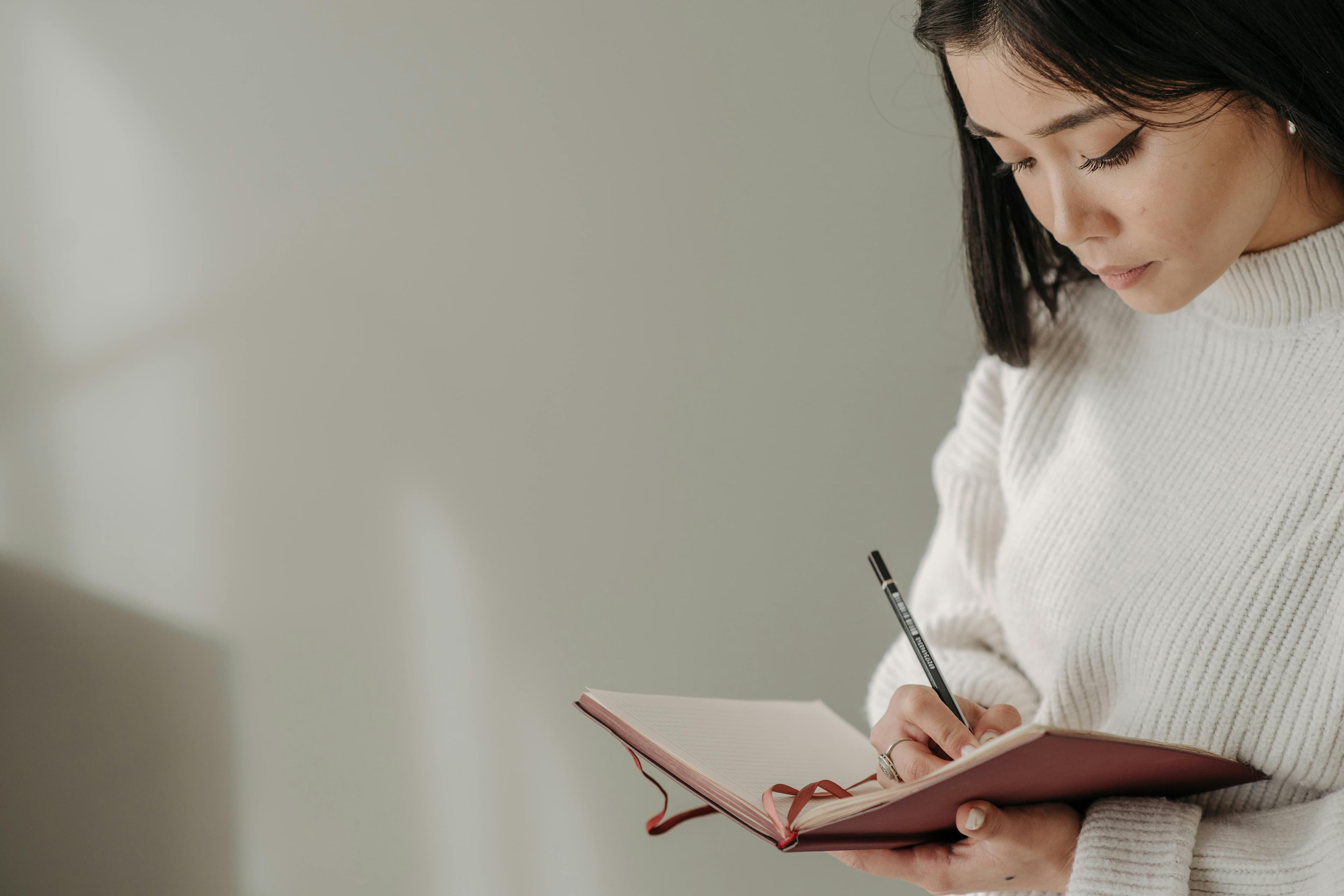 Author writing in a notebook by soft window light